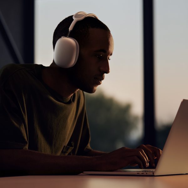 man wearing airpods max while working on macbook